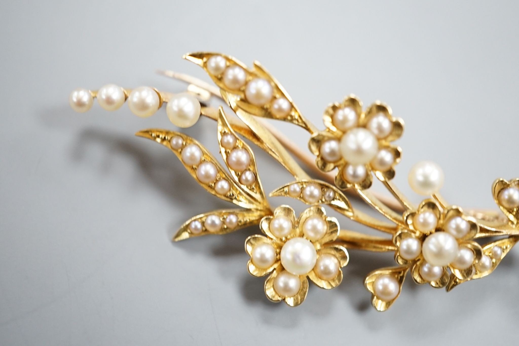 An Edwardian yellow metal and seed pearl set spray brooch, 58mm, gross weight 8.7 grams.